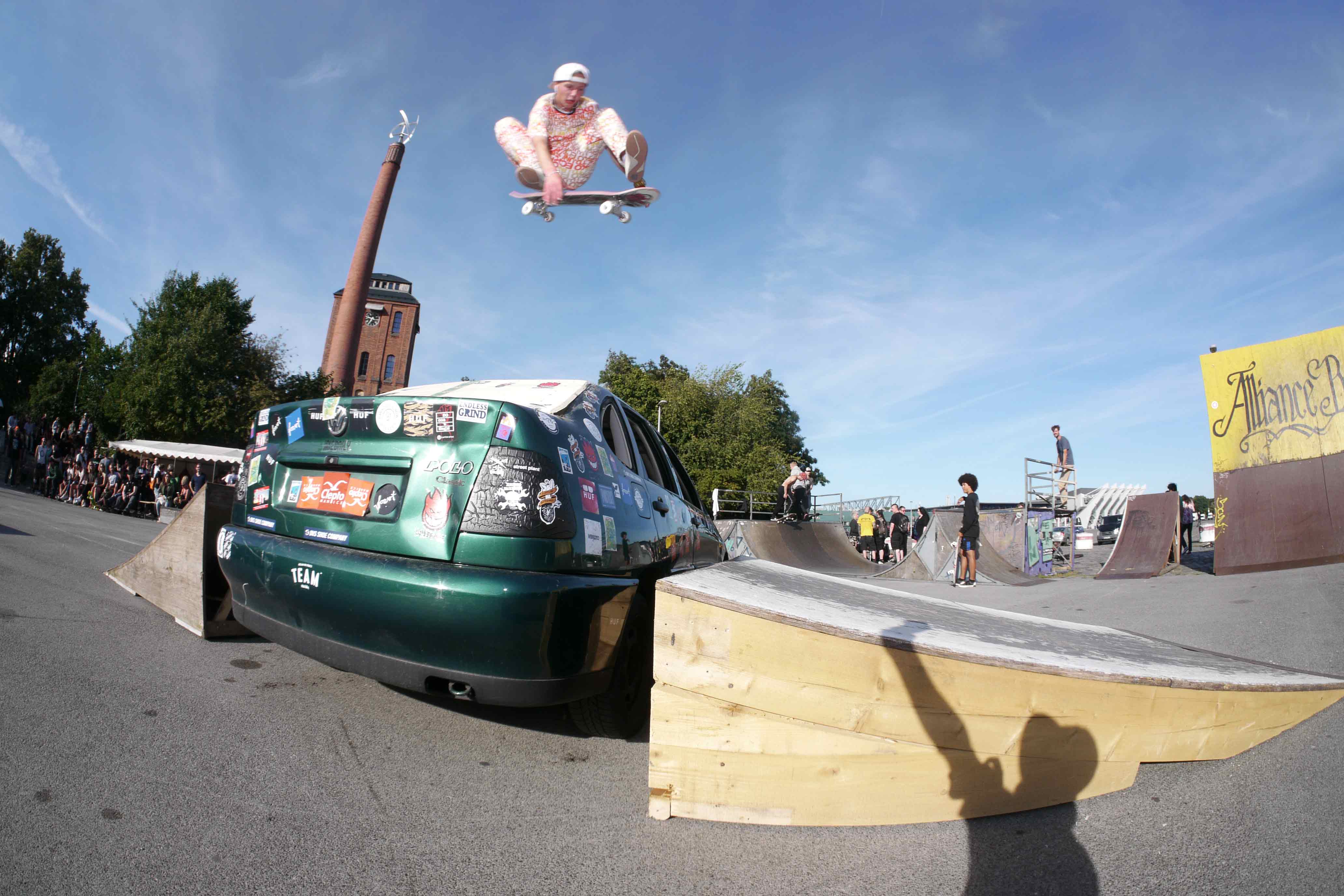 Ein Skater springt mit seinem Skateboard &uuml;ber ein altes Auto.